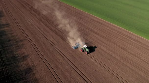 Vue aérienne d'un tracteur en mouvement avec une charrue soulevant de la poussière préparant le champ à l'ensemencement 