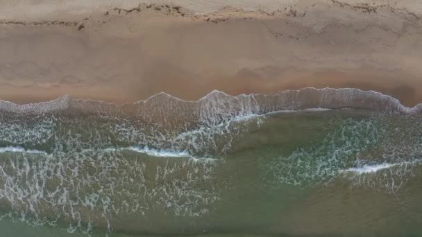 Vol par drone au-dessus de la plage sauvage et de la mer verte turquoise, au-dessus des vagues et du sable 
