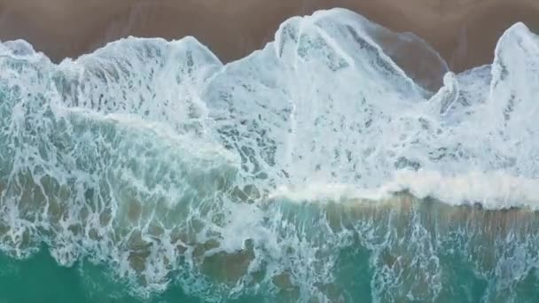 Vol par drone au-dessus de la plage sauvage et de la mer verte turquoise, au-dessus des vagues et du sable 