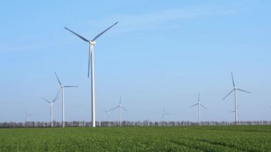 Bahar tarlaları boyunca rüzgar türbinlerinin etrafında uçan hava. Temiz ve Yenilenebilir Rüzgâr Güç Çiftliği hareket halinde. Yeşil enerji, sürdürülebilir alternatif elektrik, kirlilik ortamı yok.