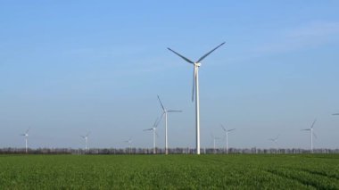 Bahar tarlaları boyunca rüzgar türbinlerinin etrafında uçan hava. Temiz ve Yenilenebilir Rüzgâr Güç Çiftliği hareket halinde. Yeşil enerji, sürdürülebilir alternatif elektrik, kirlilik ortamı yok.