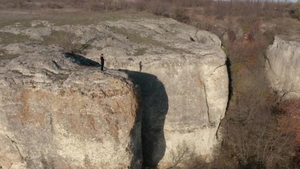 Vol aérien autour d'une jeune femme prenant des photos sur son téléphone intelligent tout en se tenant au bord de la formation rocheuse étonnante entourée par la forêt d'automne 