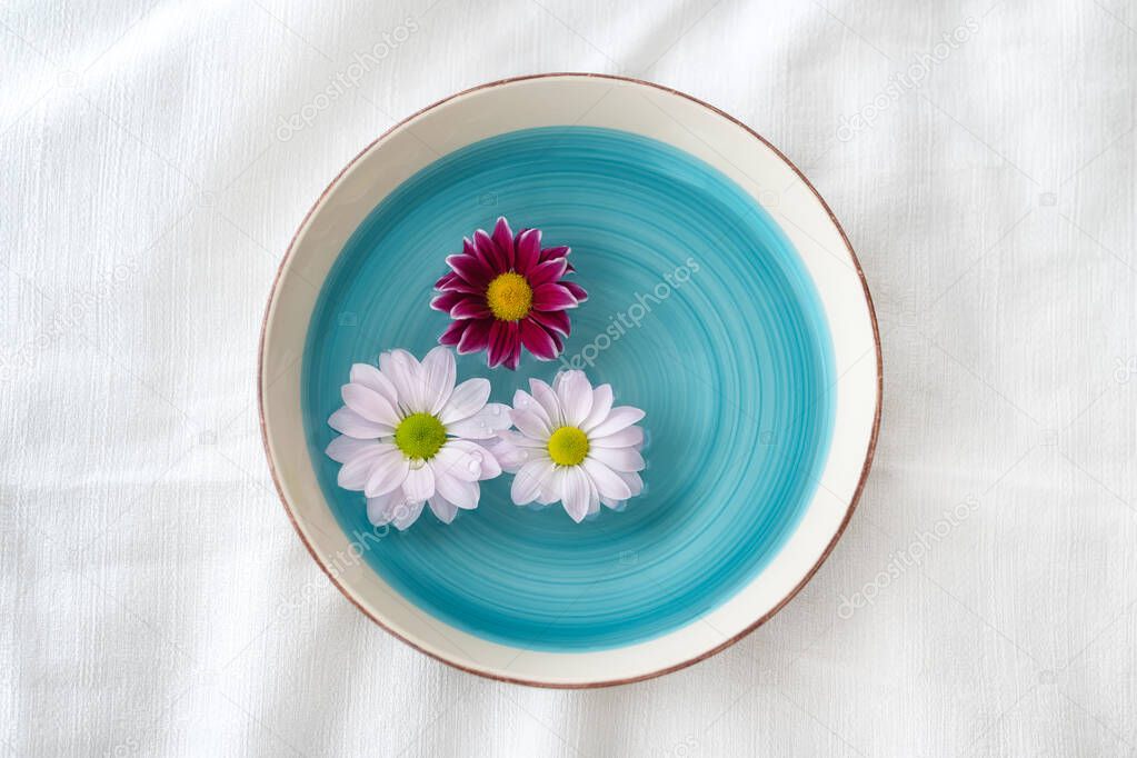 Flower decoration with white and purple daisies, floating in a vintage bowl 