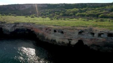 Yeşil tarlaları ve ağaçları olan kayalık kıyı şeridi boyunca yürüyorum. Yailata 'da bahar zamanı - antik mağara şehri ile ulusal arkeoloji ve doğa rezervi.