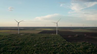 Bahar tarlaları boyunca rüzgar türbinlerinin etrafında uçan hava. Temiz ve Yenilenebilir Rüzgâr Güç Çiftliği hareket halinde. Yeşil enerji, sürdürülebilir alternatif elektrik, kirlilik ortamı yok. Görüntüyü kapat.