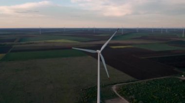 Bahar tarlaları boyunca rüzgar türbinlerinin etrafında uçan hava. Temiz ve Yenilenebilir Rüzgâr Güç Çiftliği hareket halinde. Yeşil enerji, sürdürülebilir alternatif elektrik, kirlilik ortamı yok. Görüntüyü kapat.