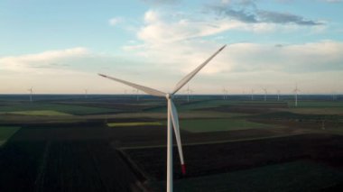 Bahar tarlaları boyunca rüzgar türbinlerinin etrafında uçan hava. Temiz ve Yenilenebilir Rüzgâr Güç Çiftliği hareket halinde. Yeşil enerji, sürdürülebilir alternatif elektrik, kirlilik ortamı yok. Görüntüyü kapat.