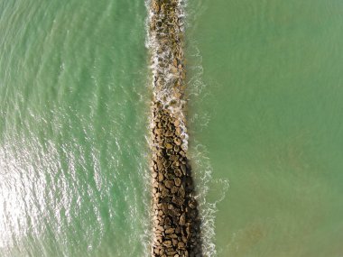Ufuk çizgisine bakan hava kaydı, dalgaların dalgalanması Akdeniz 'e karşı, yeşil ve berrak su, açık mavi gökyüzü, Santa Maria, Cadiz, Endülüs limanında alçak gelgit.