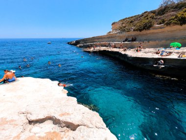 İnsanlar Malta 'nın doğal havuzunun keyfini çıkarıyor..