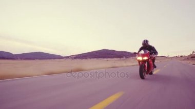 Üzerinde farlar ile gün batımında motosikletçi düz ülke yol yüksek gidiyor aşağı onun motosiklet yarış hız