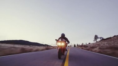 Üzerinde farlar ile gün batımında motosikletçi düz ülke yol yüksek gidiyor aşağı onun motosiklet yarış hız