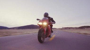 Üzerinde farlar ile gün batımında motosikletçi düz ülke yol yüksek gidiyor aşağı onun motosiklet yarış hız