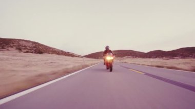 Üzerinde farlar ile gün batımında motosikletçi düz ülke yol yüksek gidiyor aşağı onun motosiklet yarış hız