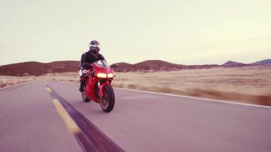 Üzerinde farlar ile gün batımında motosikletçi düz ülke yol yüksek gidiyor aşağı onun motosiklet yarış hız