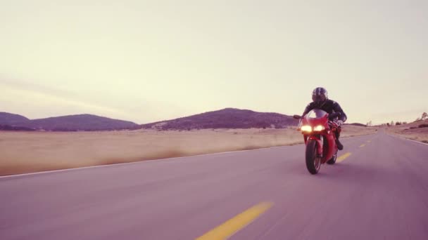 电单车司机赛车他的摩托车直乡村路走在日落与车头灯的高速 — 图库视频影像