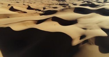 Çölde kum tepeleri üzerinde günbatımında uçan havadan görünümü