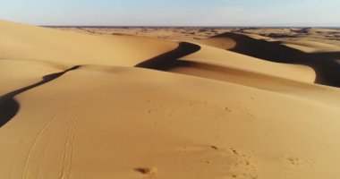 Çölde kum tepeleri üzerinde günbatımında uçan havadan görünümü