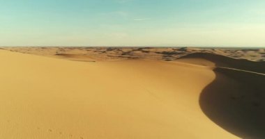 Çölde kum tepeleri üzerinde günbatımında uçan havadan görünümü