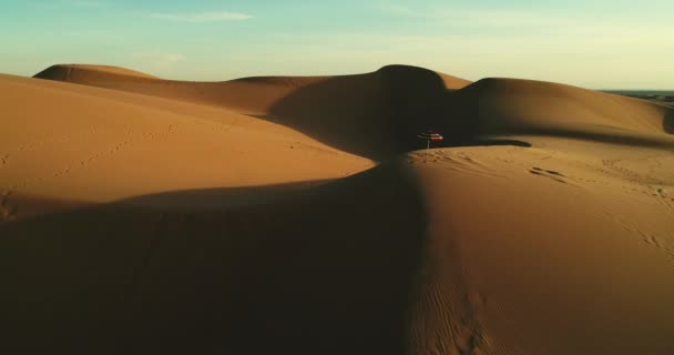 夕阳下沙漠沙丘上的彩色沙滩伞空中飞行 — 图库视频影像