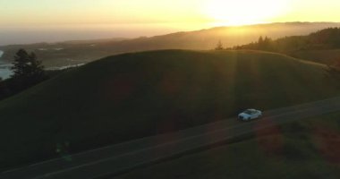 Arka plan okyanusta ile kırsal tepeler ülkede yol aşağı günbatımında araba araba havadan görünümü