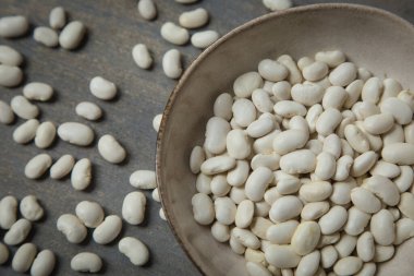 Gri bir kara zeminde, kasede çiğ beyaz fasulye..