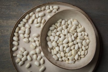 Gri bir kara zeminde, kasede çiğ beyaz fasulye..