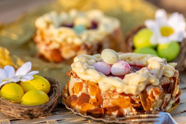 Yumurta şeklinde fındık ve oval tatlı. Beyaz papatya çiçekleri, sarı ve yeşil Paskalya yumurtaları küçük bir yuvada.