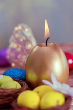Paskalya kartı yanan altın mum. Ahşap bir masa üzerinde mum ve sarı yumurta kutlaması.. 