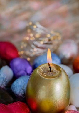 Paskalya kartı yanan altın mum ve renkli folyoyla çikolatalı yumurta. Bayramlık Paskalya konsepti