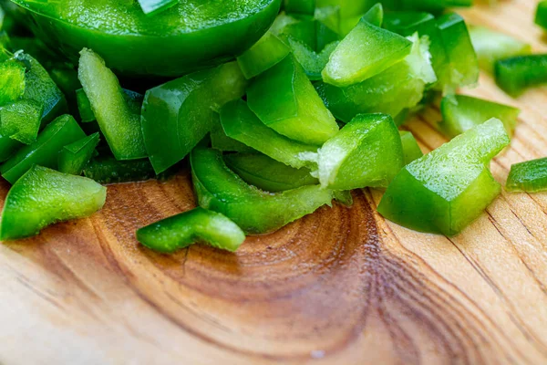 El pimiento verde dulce cortó trozos pequeños en una tabla de madera. Un pimiento picante. Comida vegetariana saludable. Macro . —  Fotos de Stock