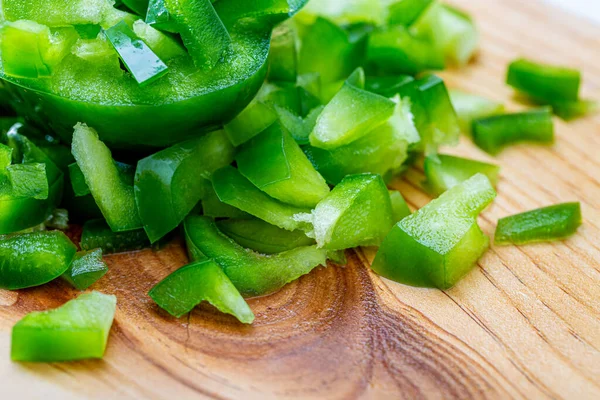Un pimiento picante. Pimienta verde dulce en rodajas pequeñas piezas en una tabla de madera húmeda. Comida vegetariana saludable. Macro . —  Fotos de Stock