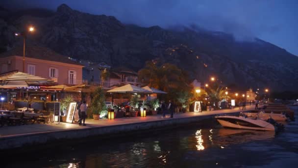 Mensen lopen langs de avondkust van de Boka baai van Kotor. Montenegro 2019 — Stockvideo