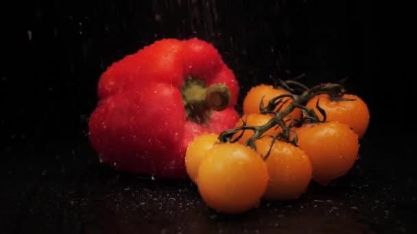 Čerstvě omytá červená paprika a žlutá třešeň na černém pozadí. Detailní záběr silného proudu vody na povrchu zeleniny. Zdravé stravování — Stock video