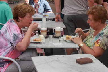Wien, Avusturya - Ağustos 2019: İki yaşlı kadın bir dilim kek yiyor ve bir kafede melankoliyi yudumluyorlar..