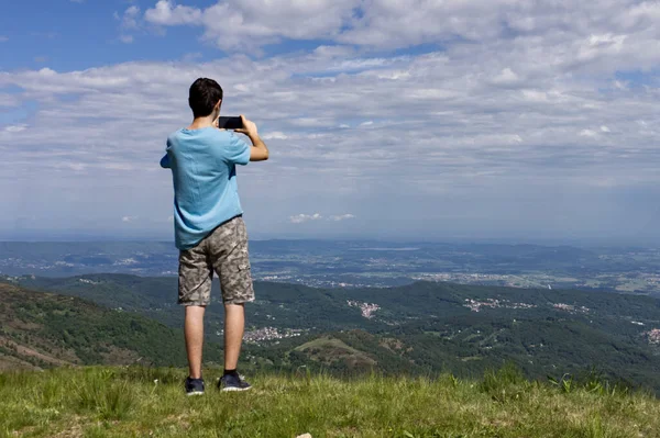 A guy takes a landscape picture with his cell phone from a vantage point — Stock Photo, Image