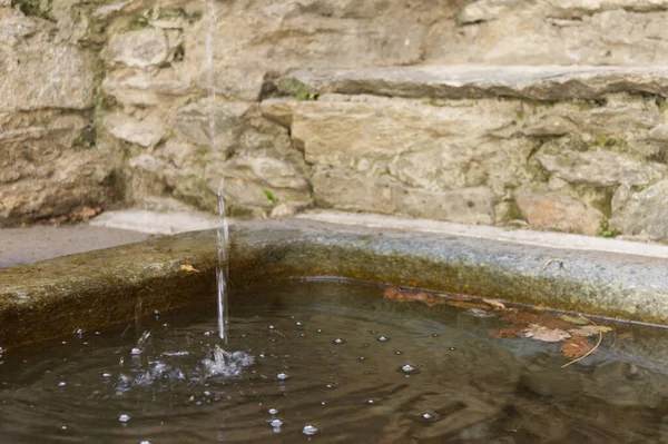 Une fontaine coule dans un réservoir de pierre dans un village alpin — Photo