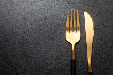 Fork and knife on a empty black plate. Close-up.