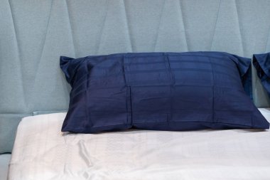 Yatağın iç dekorasyonunda açık mavi yatak başlığı olan modern mavi kumaş yastık.