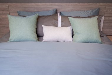 Modern kahverengi, yeşil, gri, bej renkler kahverengi yatakta kumaş yastıklar gri battaniye çarşaflar iç dekorasyon konsepti