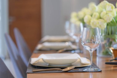 Şarap kadehi yemek masası dekorasyonu tabaklar, cam, peçeteler ile servis ediliyor ahşap yemek masası üzerinde modern konsept.