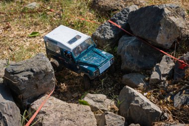 Bangkok, Thailand - December 10, 2019 : RC Radio controlled truck moves over an obstacle driving along on the rock with coast and river clipart