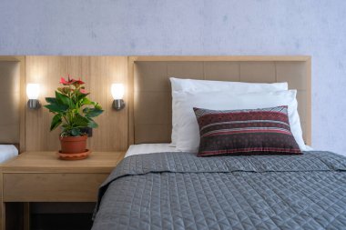 Yatak odasındaki dekoratif ağaç ve gri duvarlı iç dekorasyonlu lamba ve yatak odasındaki modern kumaş yastıklarından oluşan güzel bir grup.