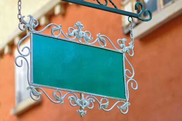 Beautiful green metal blank sign for copy space text and advertising is decorated with wrought iron motifs for shop and restaurant exterior building vintage style
