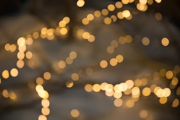 Christmas garlands with blurred focus in the form of bokeh and Golden misty haze on a dark background. Abstract colorful background with Golden bokeh. — Stock Photo, Image