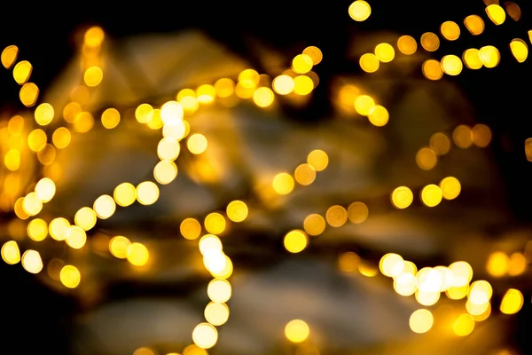 Christmas garlands with blurred focus in the form of bokeh and Golden misty haze on a dark background. Abstract colorful background with Golden bokeh. — Stock Photo, Image