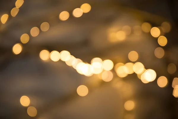 Christmas garlands with blurred focus in the form of bokeh and Golden misty haze on a dark background. Abstract colorful background with Golden bokeh. — Stock Photo, Image