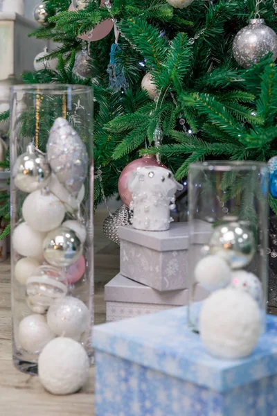 Όμορφες μπάλες του νέου έτους, γκρι και μπλε κουτιά με χριστουγεννιάτικα δώρα βρίσκονται κάτω από το δέντρο. Η έννοια της προετοιμασίας για τις γιορτές των Χριστουγέννων και τη διακόσμηση του χριστουγεννιάτικου δέντρου. — Φωτογραφία Αρχείου