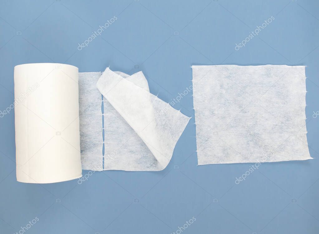Disposable synthetic non- woven cleaning cloths in a roll, on a blue background. Cosmetic towels Spunlace. The concept of personal hygiene