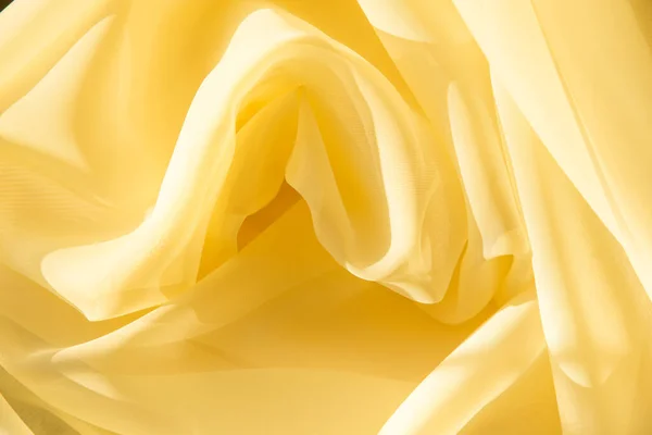 Sarı kumaşlı arka plan. Açık şeffaf kumaş ipeği ya da organza kıvrımlar halinde serilir. Yukarıdan manzara. Moda yaz tekstil ürünleri.