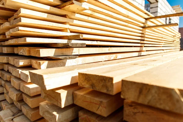 Stack of new wooden studs at the lumber yard. Timber on the construction site to dry. Background of sawed and processed wood of coniferous breeds